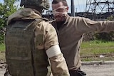 A Russian serviceman frisks a Ukrainian soldier wearing an eye patch.