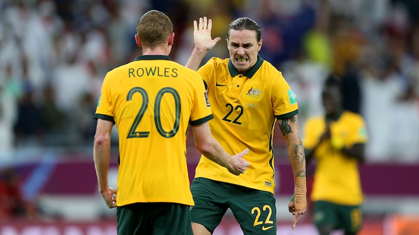 Two male soccer players in green and yellow high-five