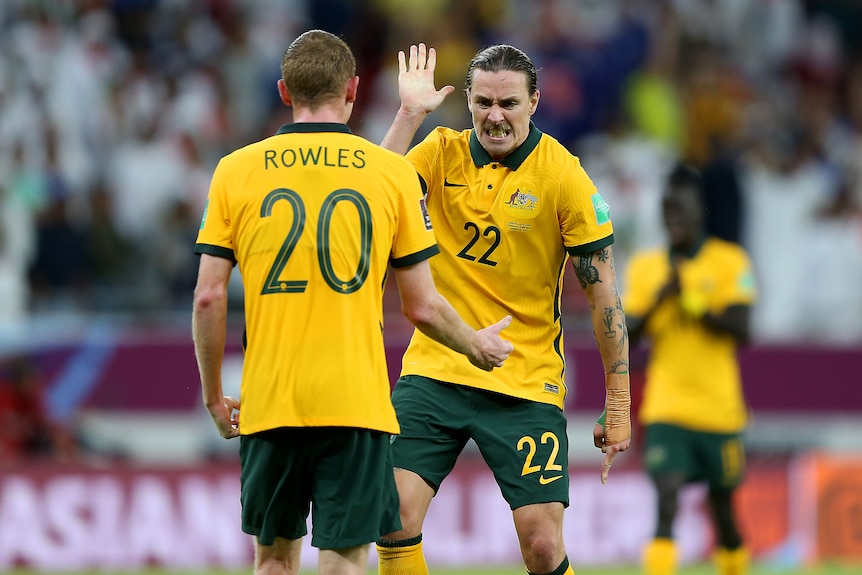 Two male soccer players in green and yellow high-five