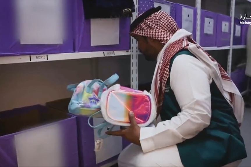 An official from the Saudi Arabian Ministry of Commerce holding rainbow-coloured bags.