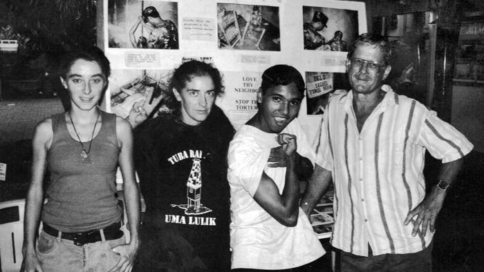 Four Timor-Leste activists stand in front of photo display