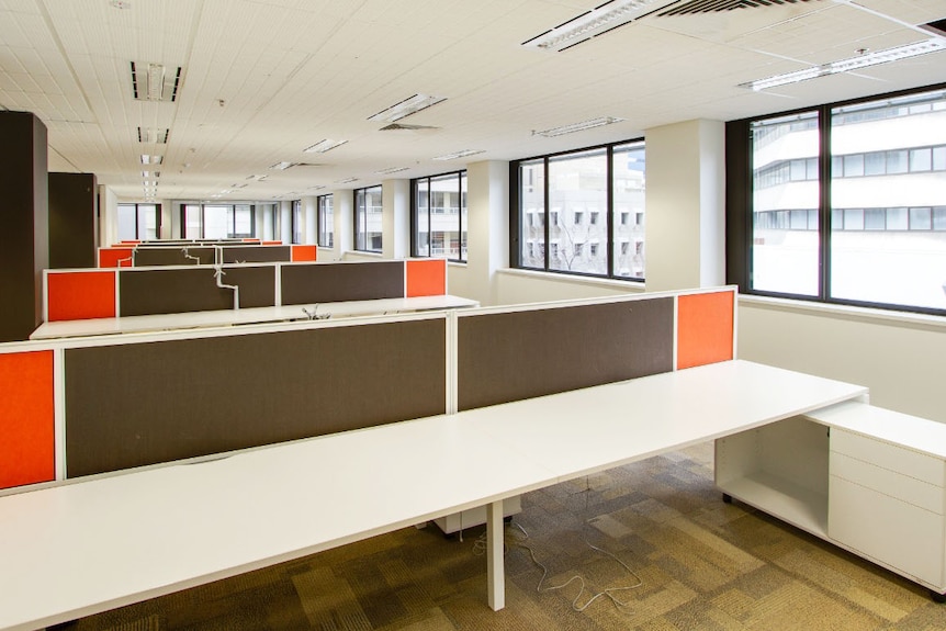 Vacant office space with empty desks separated by partitions.