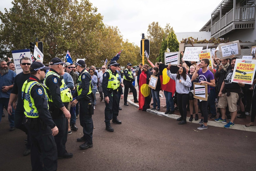 Two rival groups of protesters stand separated by police outside Julie Bishop's office in Perth.