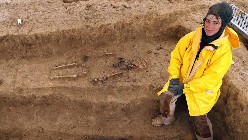 Archaeologist sits near Iron Age skeletons