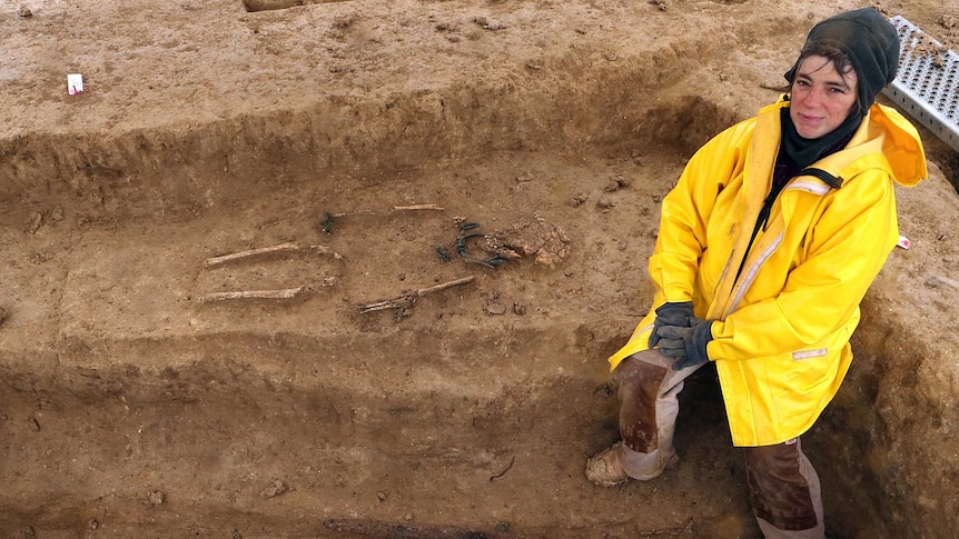 Archaeologist sits near Iron Age skeletons