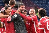 Liverpol players swarm around Alisson, who is wearing his goalkeeper kit, in wild celebration