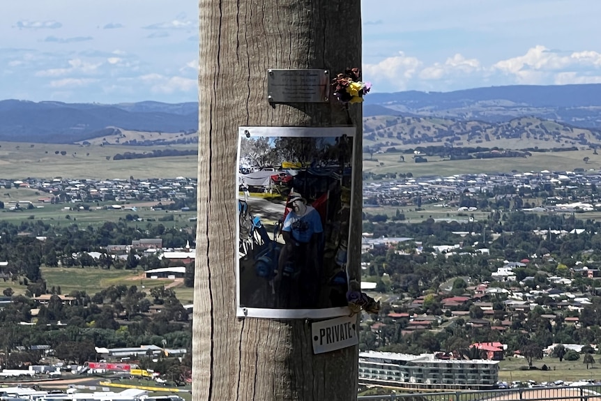 Placa de metal y un tributo fotográfico en un poste de energía en la cima del monte Panorama.