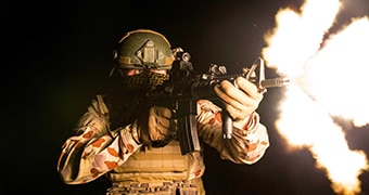 A blast of fire shoots out of a soldier's rifle.