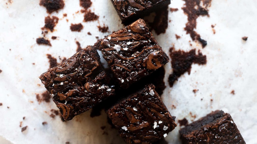 Squares of chocolate brownies with sea salt and salted caramel swirls illustrating our simple recipes.