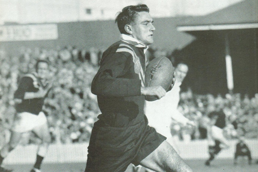 A black and white photo of Reg Gasnier running with the ball for Australia.