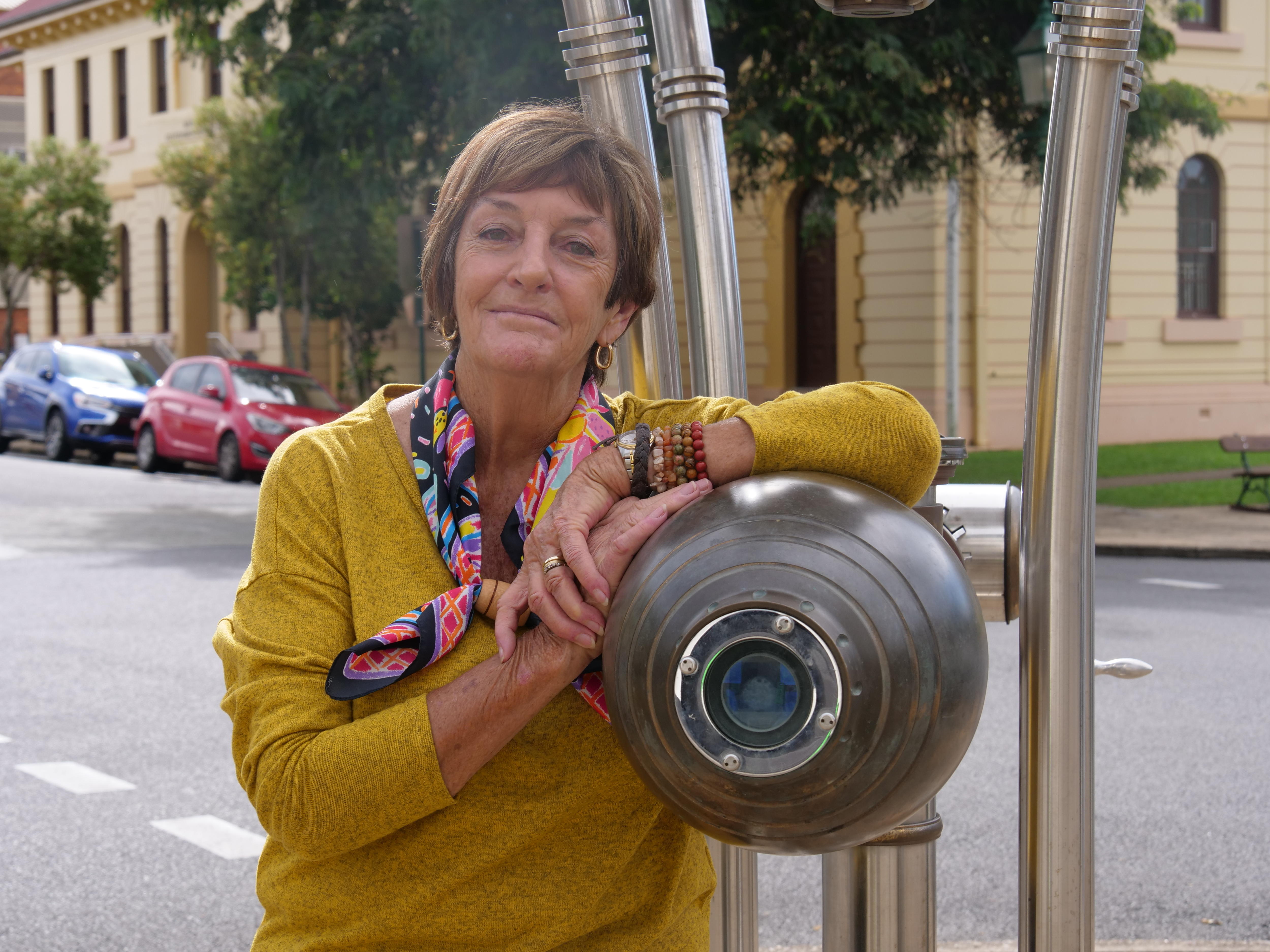 An older woman is leaning against an interesting historical machine.