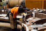 An apprentice working with machinery in the workshop.