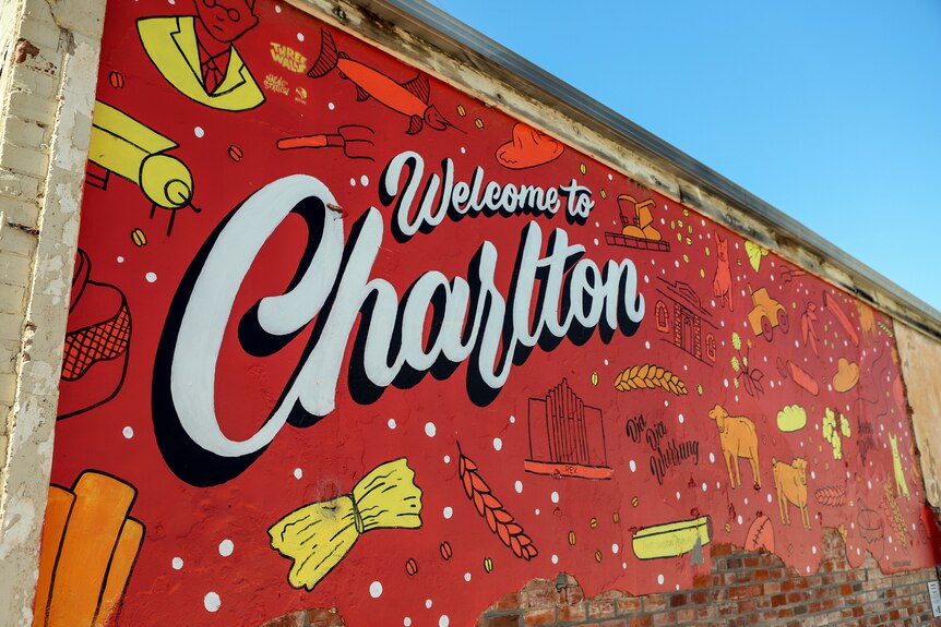 Welcome to Charlton text written in large font on a red street wall beneath blue sky
