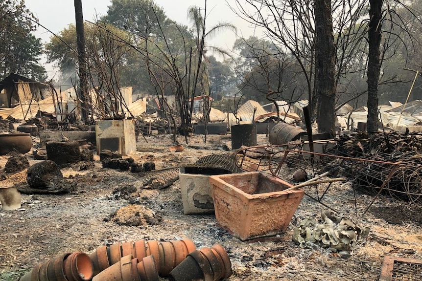 Burnt and twisted metal is strewn between terracotta pots in the wreckage of a home.