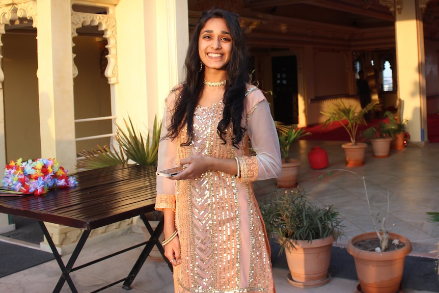 Indian Australian Yatha Jain is wearing a cream-coloured sari and is standing facing the camera and smiling.