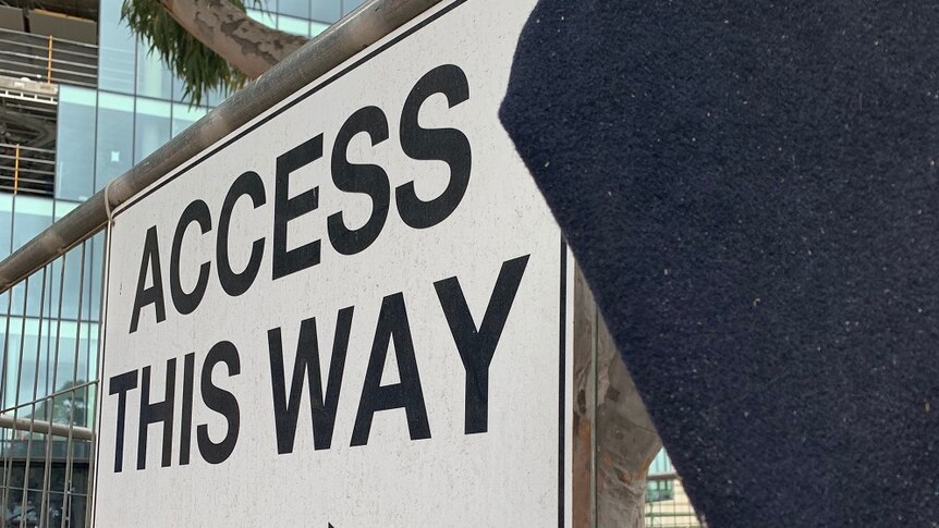 A sign that says access this way on a construction site.