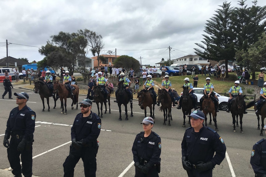 A line police on horses stand in a car park.