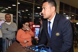 Israel Folau pushes his baggage through Sydney International Airport after returning from the Rugby World Cup.