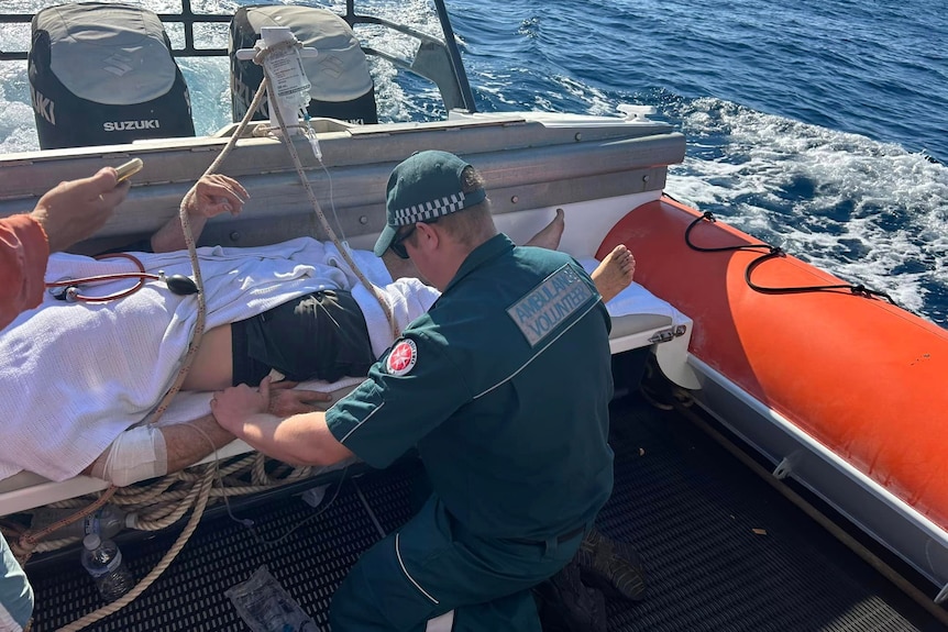 A man paramedic attends to a man on a stretcher onboard a boat