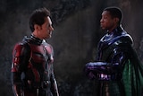 Two men in superhero costumes face each other looking serious.