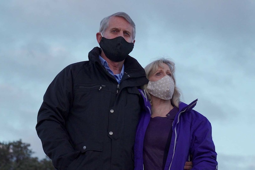 A man and woman both wear face masks.