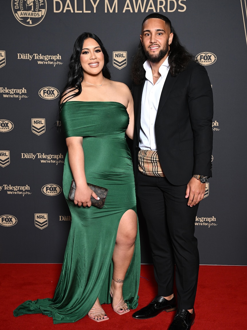 A woman in a green dress next to a man in a suit on the red carpet. 