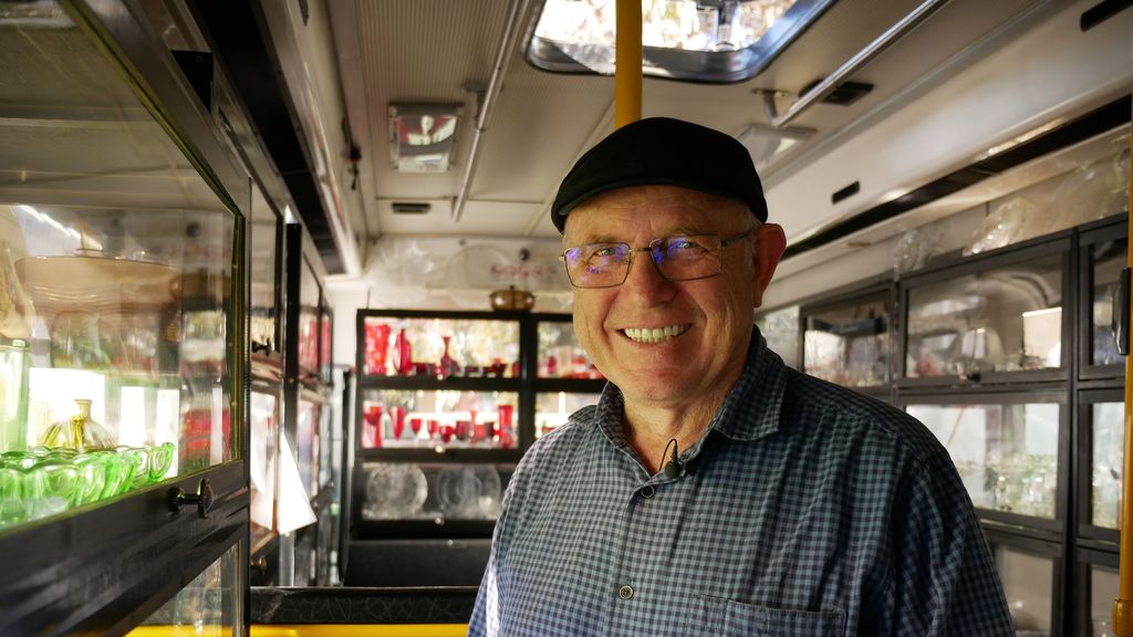 Man smiling. Wearing a blue check shirt and a hat. 