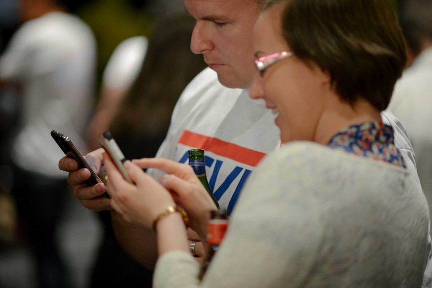 Siobhan Keating and Paul Watson look at the results for the 2013 Federal election on their phones.