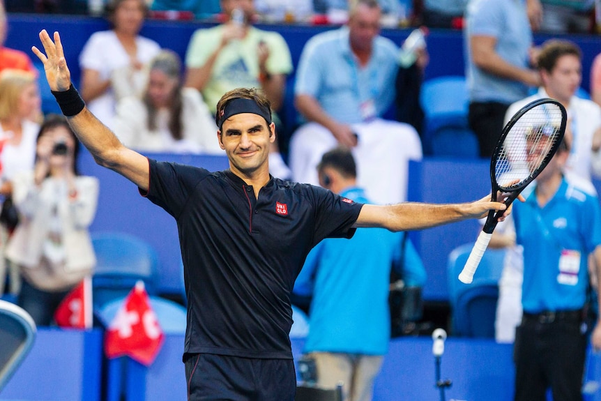Roger Federer holds his arms out wide in celebration of a win.