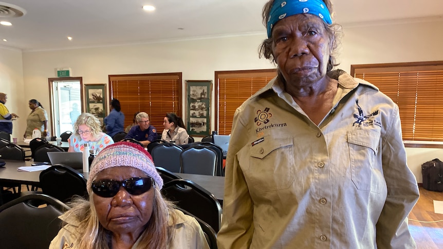 Two older women are in frame, one is sitting and the other is standing. They are in ranger uniforms and have sunglasses on.