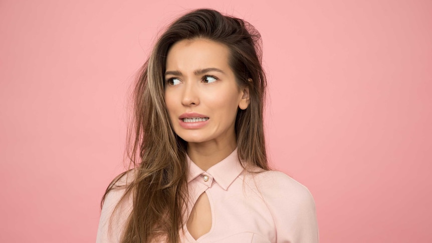 Woman looking anxious and confused with a pink background