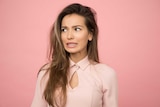 Woman looking anxious and confused with a pink background