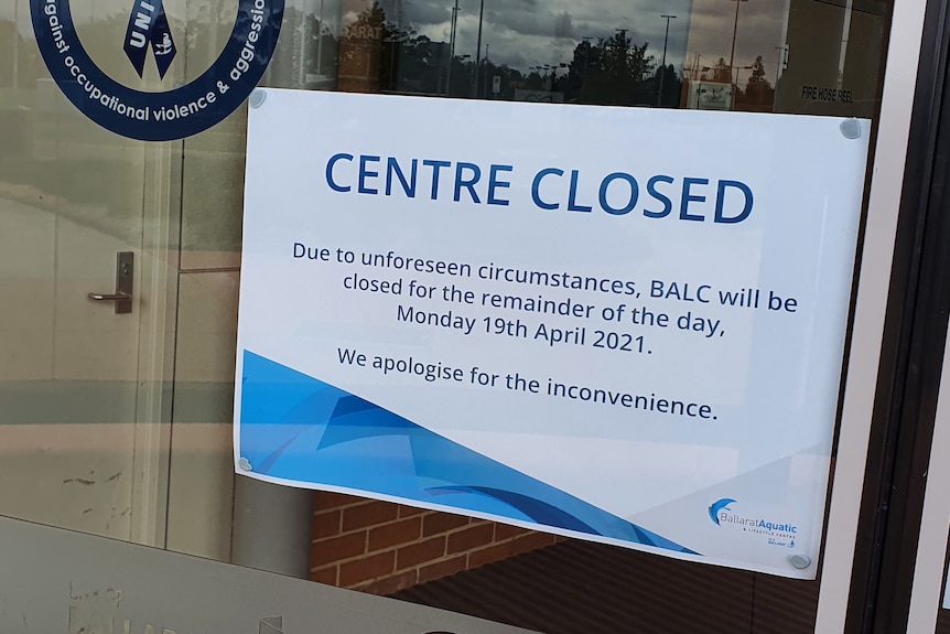 Sign attached to aquatic centre glass door saying 'centre closed'.