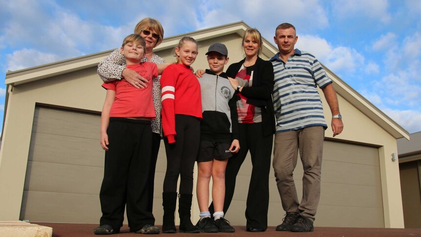 The three Antcliff children stand in front, their grandmother's arm around one, outside family home.