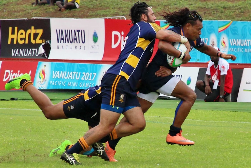 A Solomons player attempts to break free of a tackle during a game.