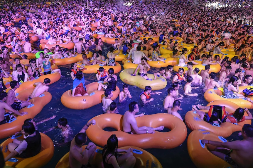 People at a pool party in Wuhan watch a performance in a swimming pool.