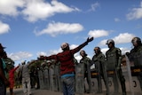 Men gesture at a row of soldiers wearing riot gear who are blocking the Venezuelan border.