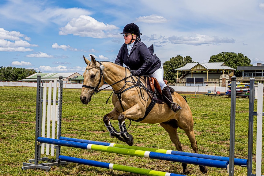 Felicity Fraser on a horse in mid-air going over a jump.