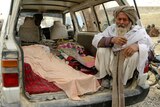 An elderly Afghan man sits next to the covered bodies of people who were killed by coalition forces in Kandahar