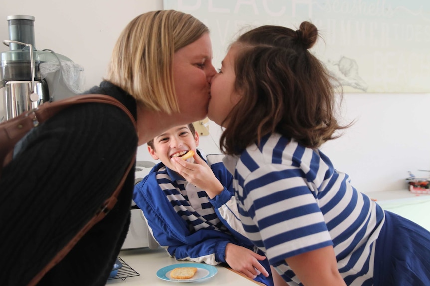 Kate Manson kisses goodbye her daughter Kayla while Noah laughs in the background, they live in a multigenerational household.