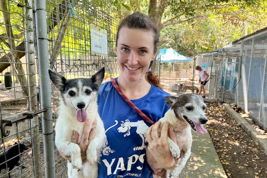 A young woman holding two small dogs