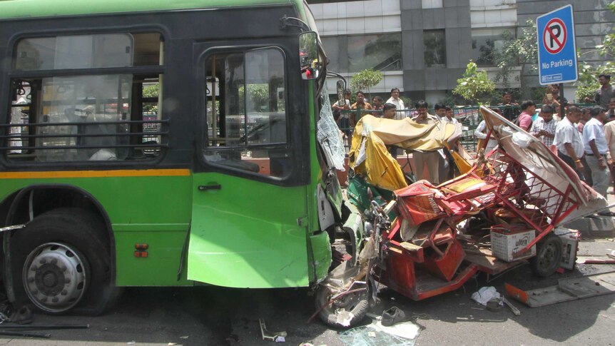 The scene after a green bus collided with two rickshaws, one red and one yellow and green. The smaller vehicles are crushed.