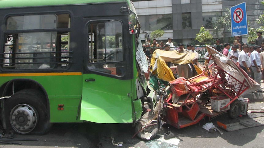 The scene after a green bus collided with two rickshaws, one red and one yellow and green. The smaller vehicles are crushed.