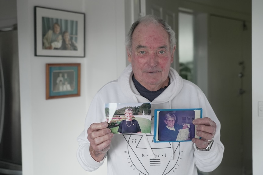 A man holds two photos of a woman.