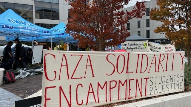 A large banner that says "Gaza Solidarity Encampment: Students 4 Palestine" in front of tents 