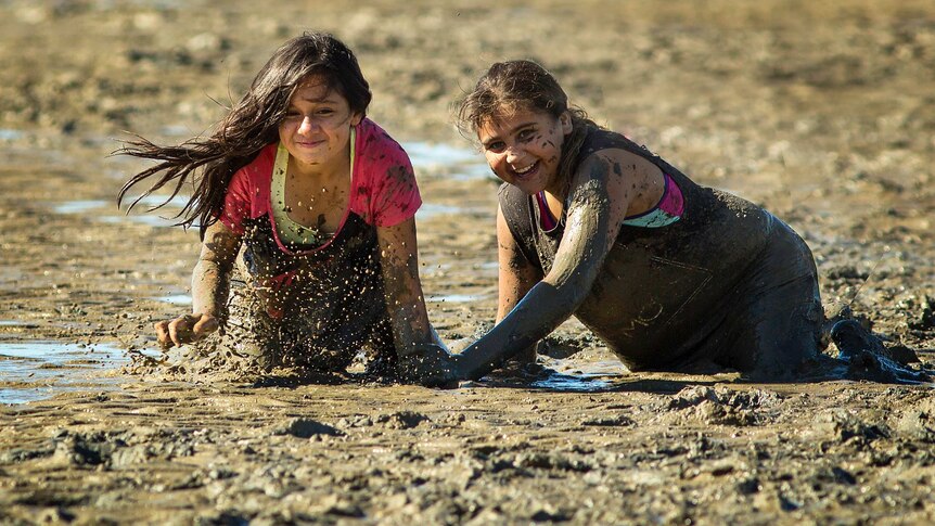 Two girls play in the mud