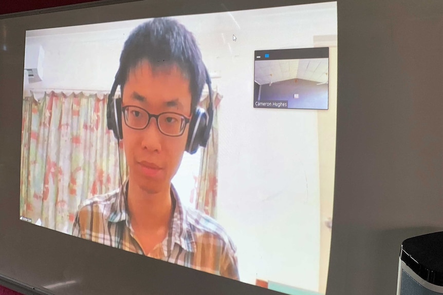 A projection of St John's teacher Victor Sun on the wall of his classroom while he is at home
