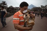 A resident cradles his dog after rescuing him near the Volcan de Fuego
