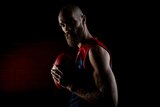 An AFL team captain stands in shadow as he looks at the camera holding a football.