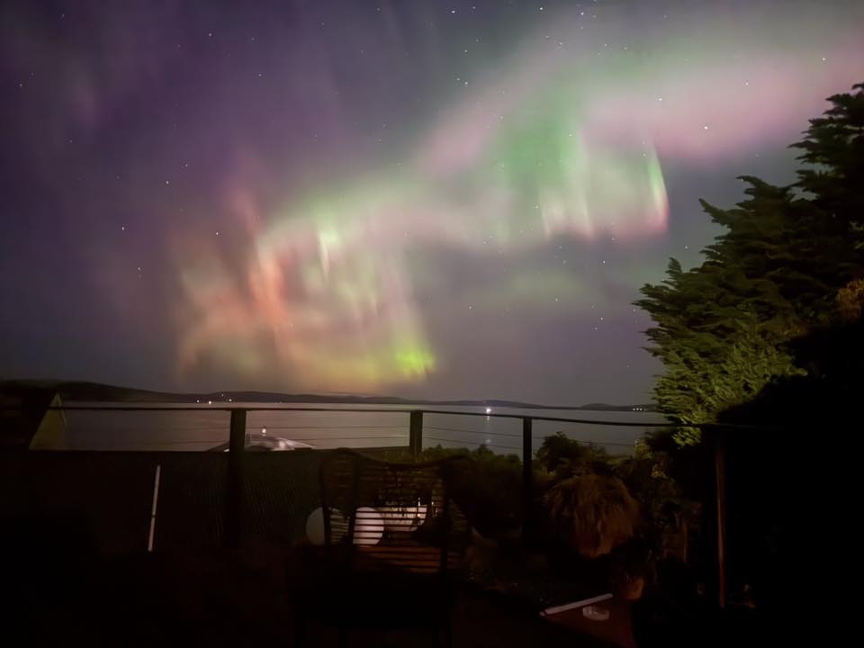 Luces rosas, amarillas, verdes, violetas y rojas se arremolinan en el cielo sobre una balaustrada.
